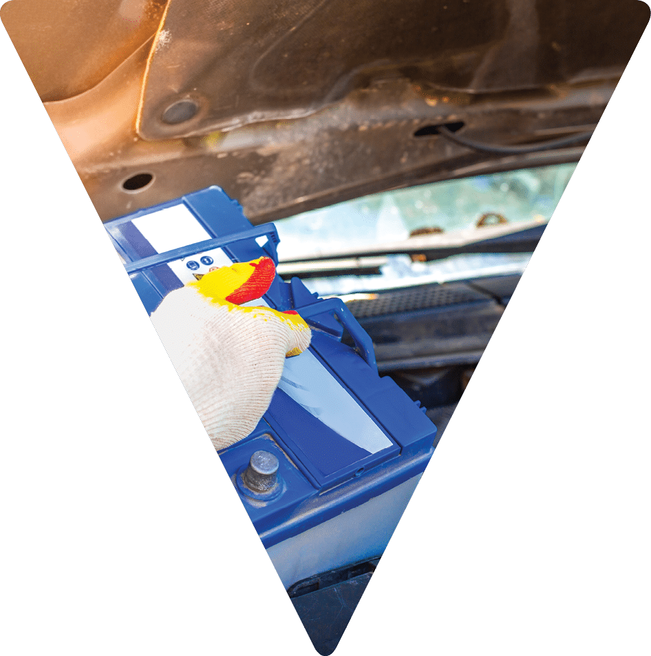 Maintenance of the machine  A male car mechanic takes out a battery from under the hood of a auto to repair, charge or replace it 