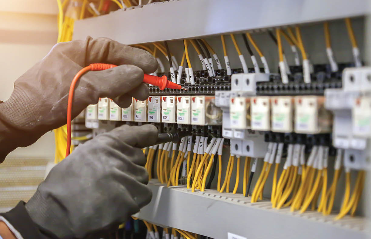 Electrical engineer using digital multi meter to check current voltage at circuit breaker in main distribution board 