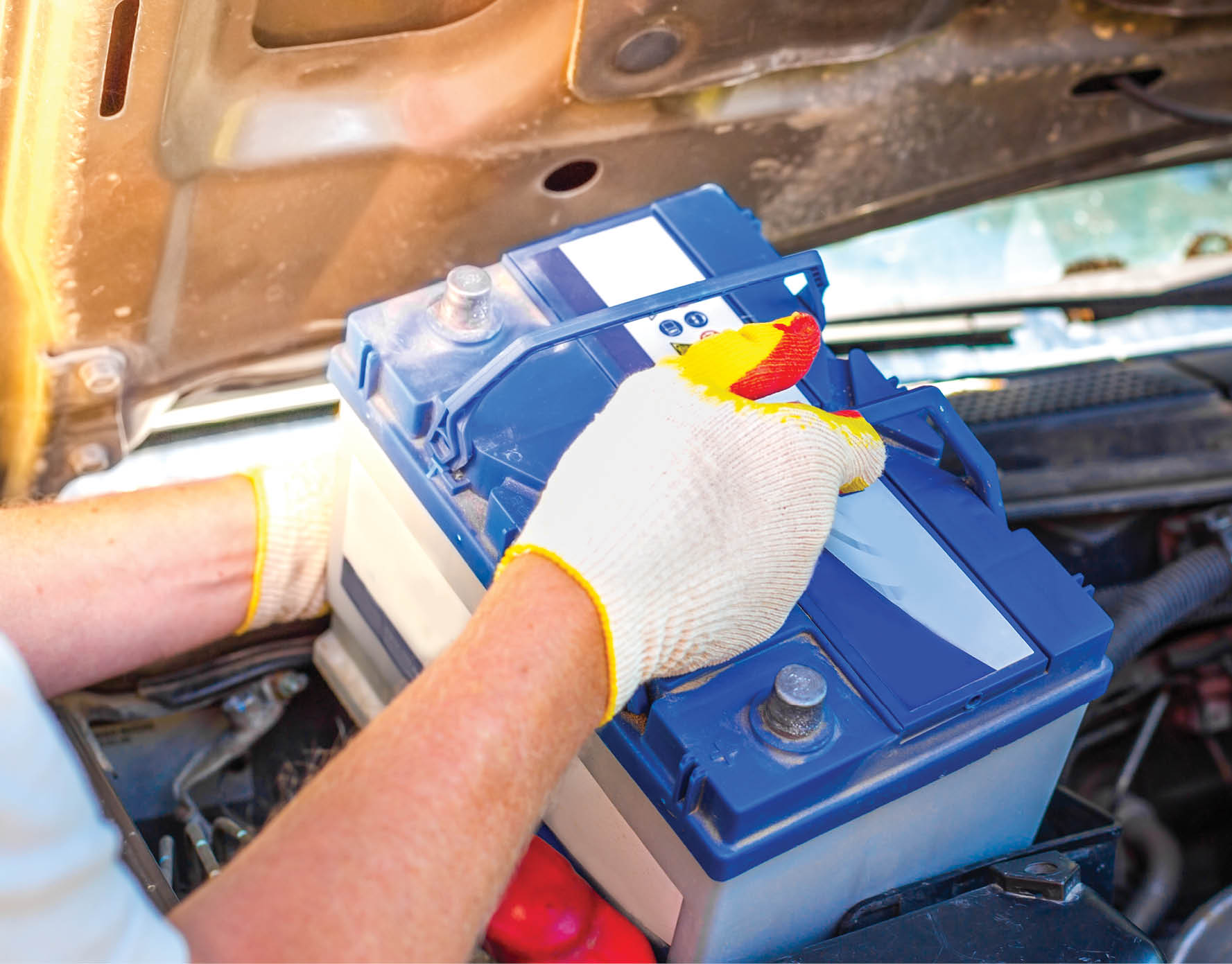Maintenance of the machine  A male car mechanic takes out a battery from under the hood of a auto to repair, charge or replace it 