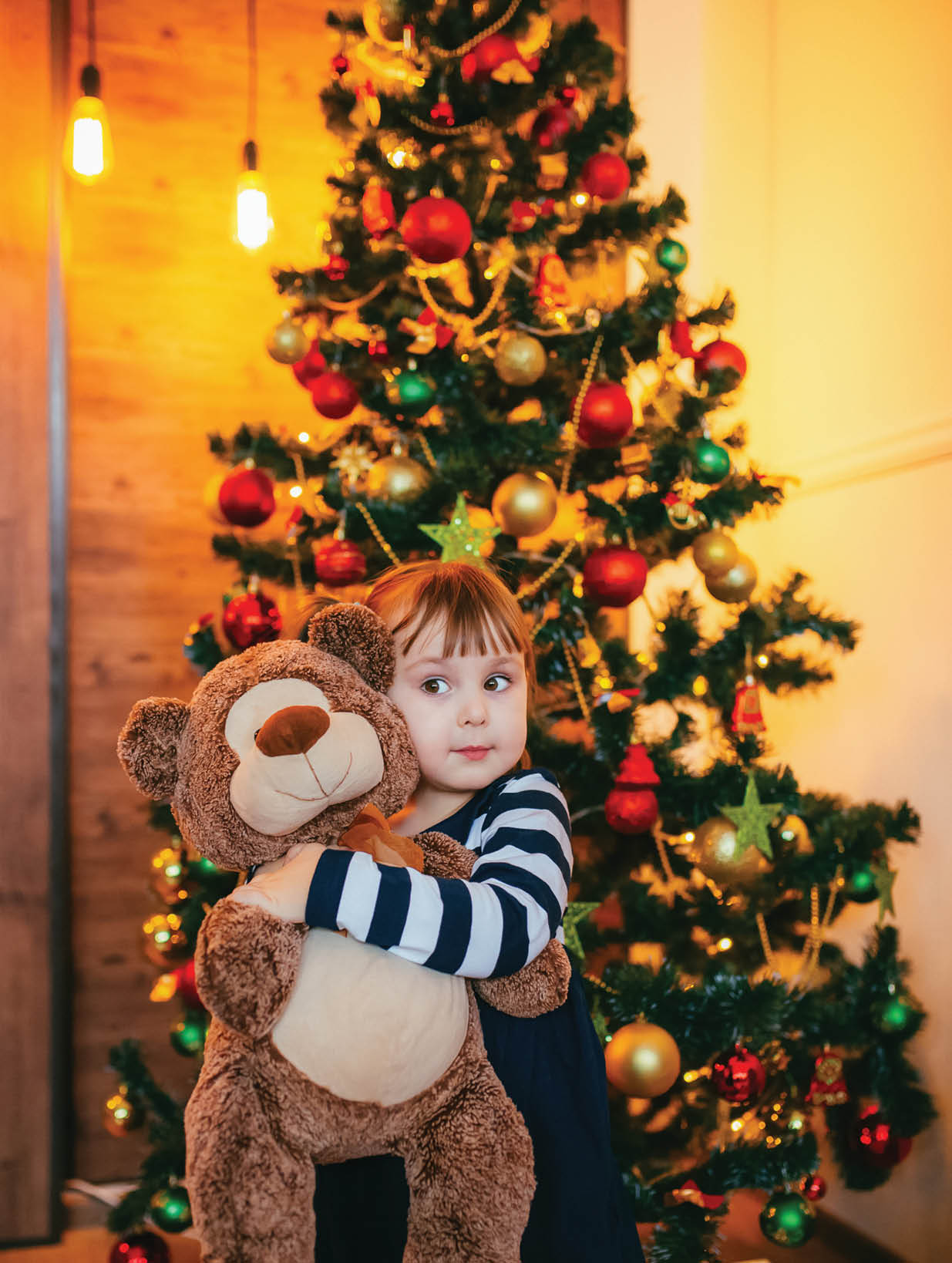 A little girl is enjoying her new teddy bear given by Santa Claus for Christmas  Female child with teddy bear  New year decor