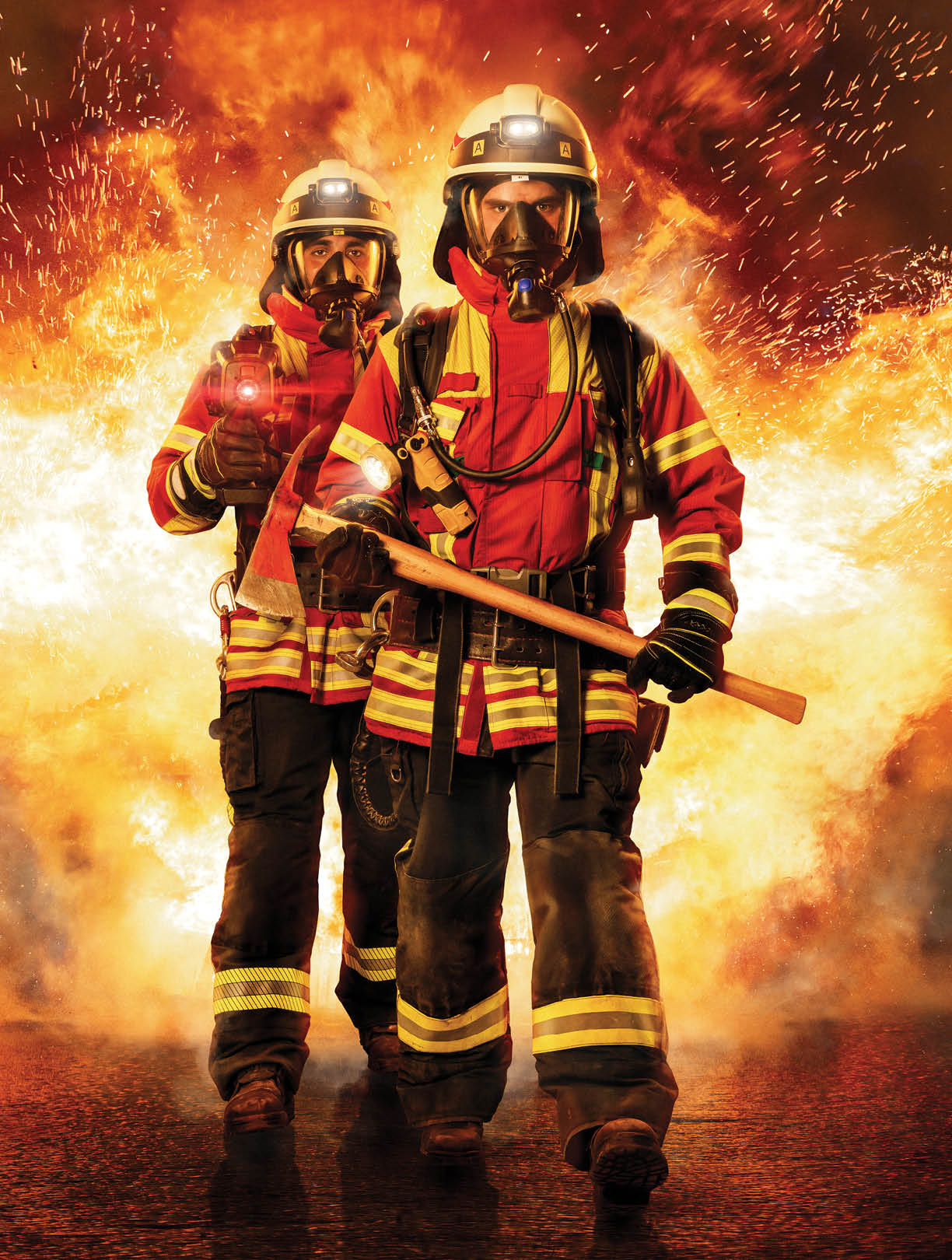 Zwei Feuerwehrmänner laufen unter Atemschutz und schwerer Ausrüstung durch das Feuer um Menschen zu retten 