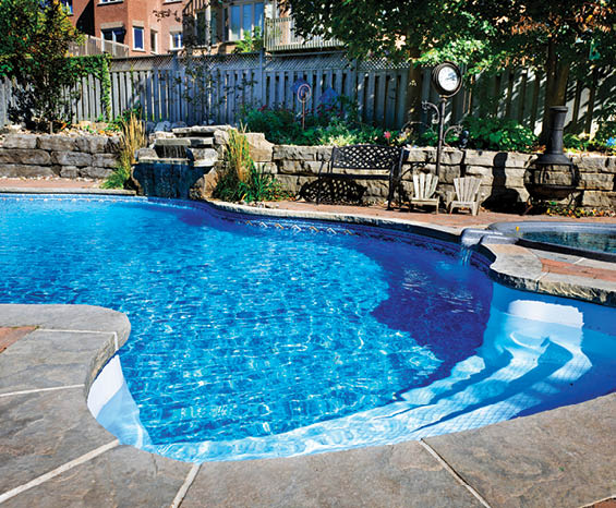 Residential inground swimming pool in backyard with waterfall and hot tub