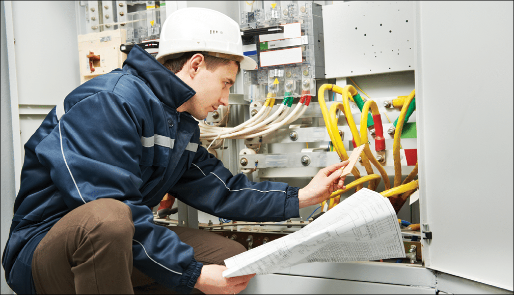 Electrician builder at work inspecting cabling connection of high voltage power electric line in industrial distribution fuseboard