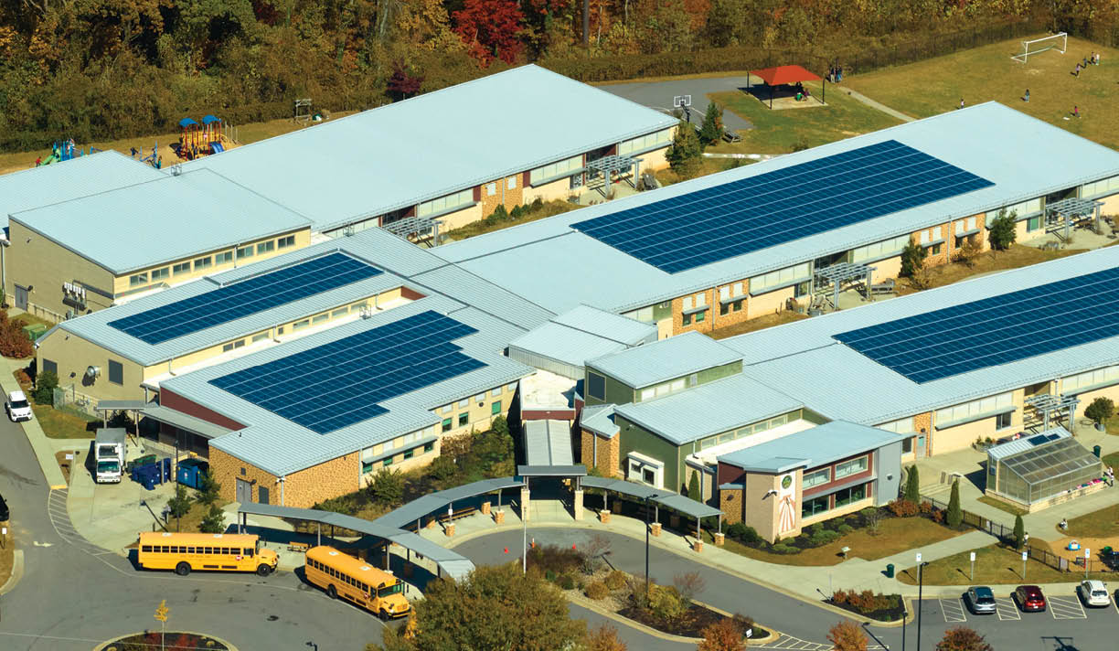 Aerial view of american school building with rooftop covered with photovoltaic solar panels for production of electric energy.