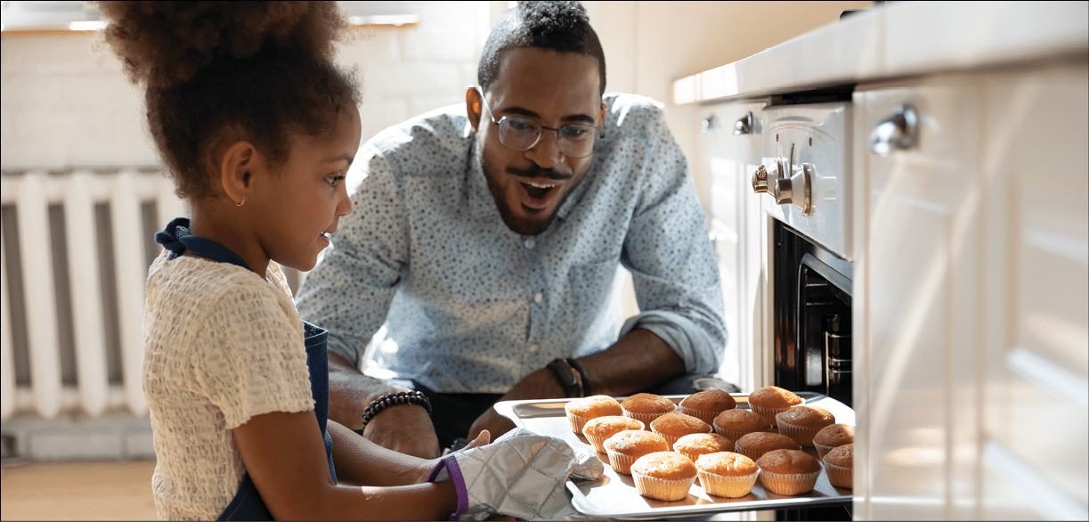 Wow, looks great! Excited caring millennial african dad or grown elder brother watching concentrated small black daughter or younger preteen sister taking pan with self baked tasty muffins out of oven