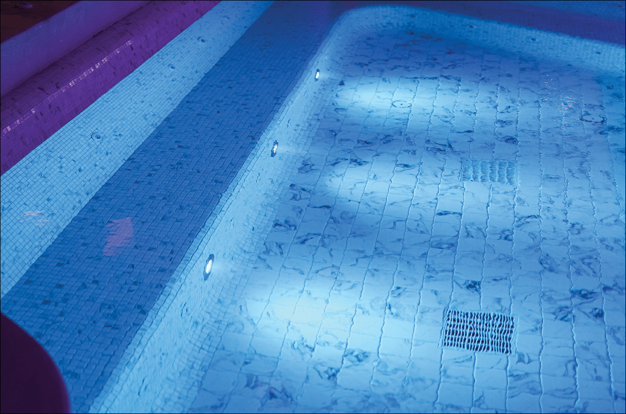 A luxury swimming pool with clearly transparent water and white marble tile floor. Building place photo, selective focus at marble tile. Photo contained some noise due to low light environment.