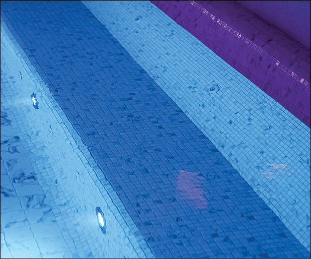 A luxury swimming pool with clearly transparent water and white marble tile floor. Building place photo, selective focus at marble tile. Photo contained some noise due to low light environment.