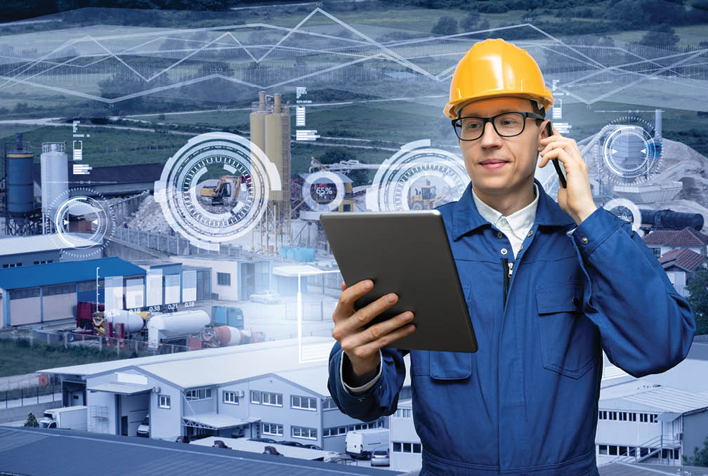 Engineer with digital tablet and smartphone on a background of modern smart factory. Digital transformation and industry 4.0