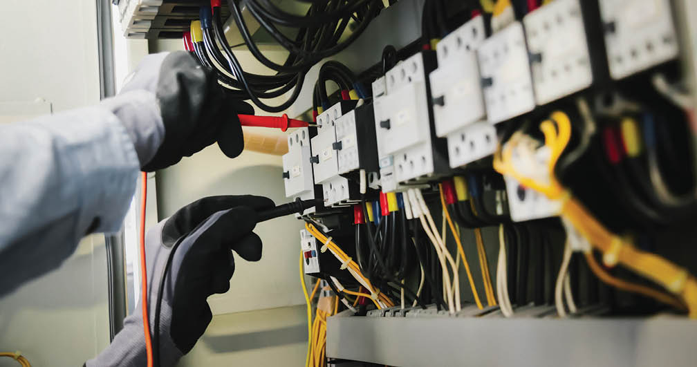 Electrical engineers test electrical installations and wiring on protective relays, measuring them with a multimeter.