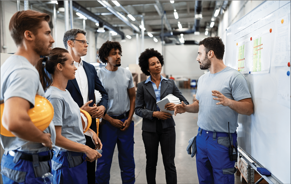 Young factory worker holding presentation about production development to company managers and his coworkers.