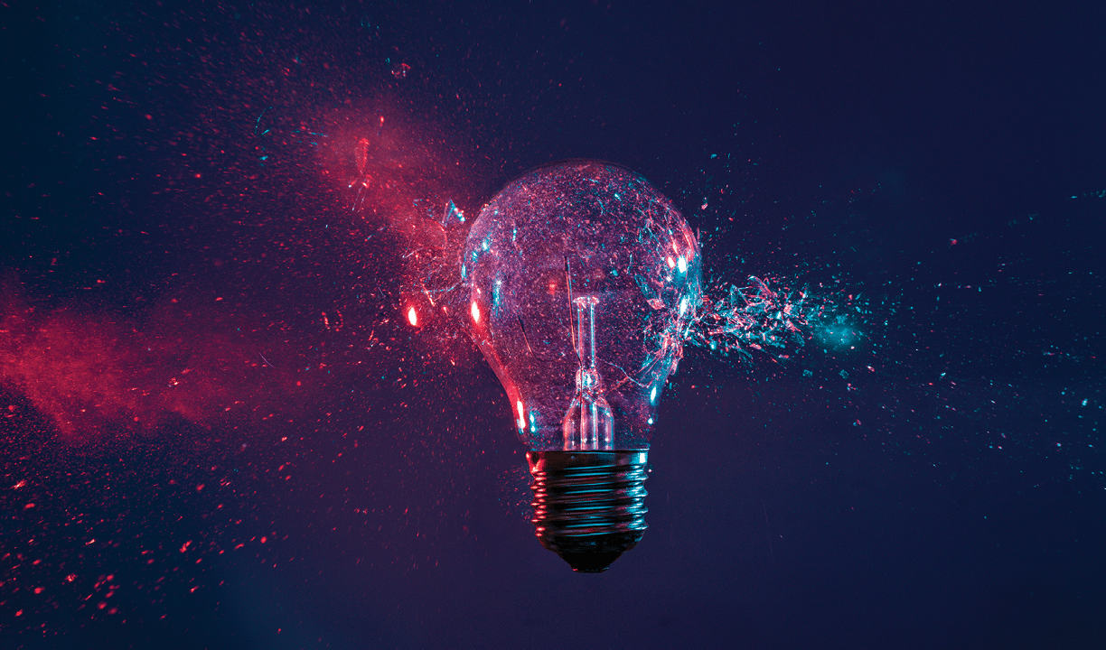 High speed studio photography, moment of the impact of a bullet on a classic electric bulb. Detail of glass explosion, blue and purple lighting. Concept of obsolete energy.