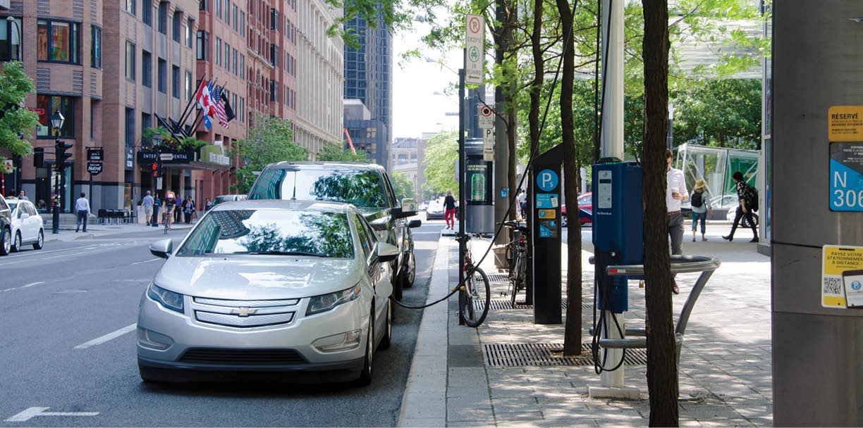 Montreal, Quebec, Canada - 20 July 2016: Electric car charging at recharging station in the street under green trees in summertime as editorialMontreal, Quebec, Canada - 20 July 2016: Electric car charging at recharging station in the street under green trees in summertime as editorial