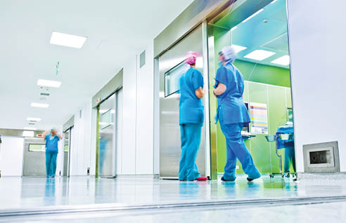 blurred figures wearing medical uniforms in hospital surgery corridor