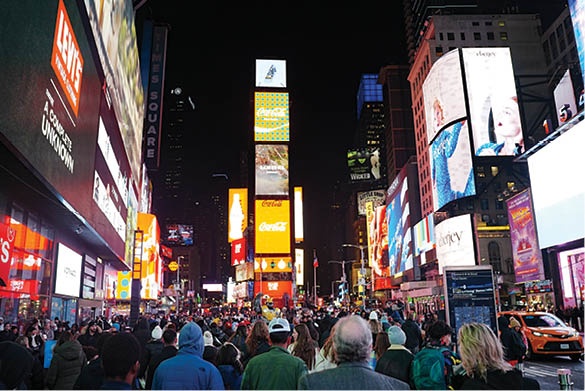 A vibrant night shot of Times Square in New York City, where dazzling billboards and neon lights illuminate the streets packed with people. The photo captures the energy, color, and constant motion of this iconic intersection, where the city truly never sleeps.