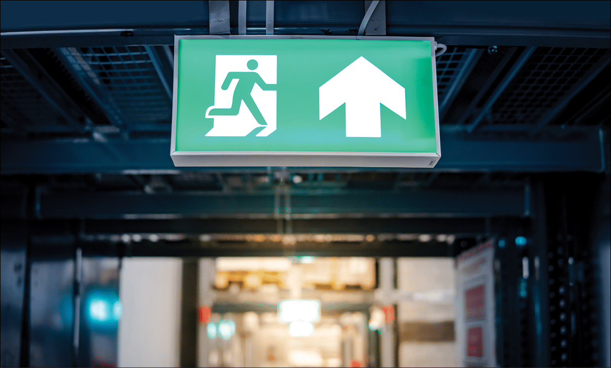 Green emergency exit sign or fire exit sign showing the way to escape with arrow symbol.