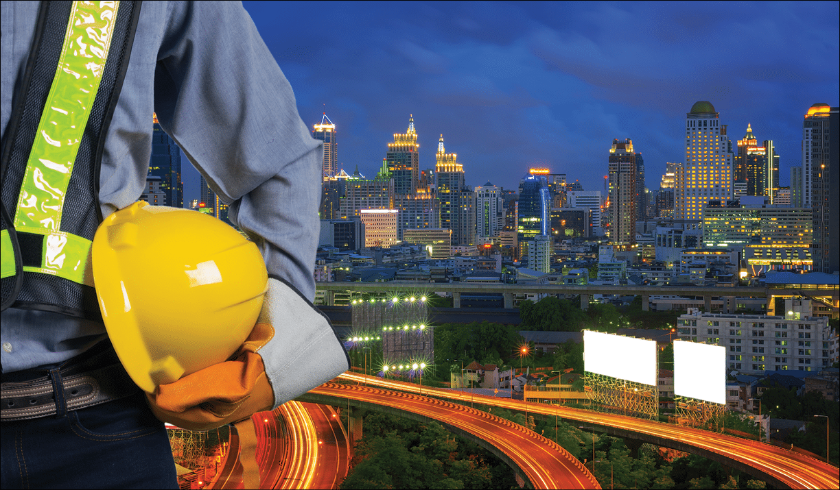 Engineer holding a yellow helmet for the safety of the workers, with expressway as a backdrop and modern building in the business district twilight time.