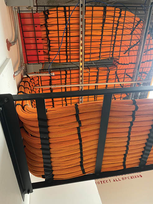 This is a photo of a ceiling containing networking cables bundled together while headed towards the Network Operations Center.