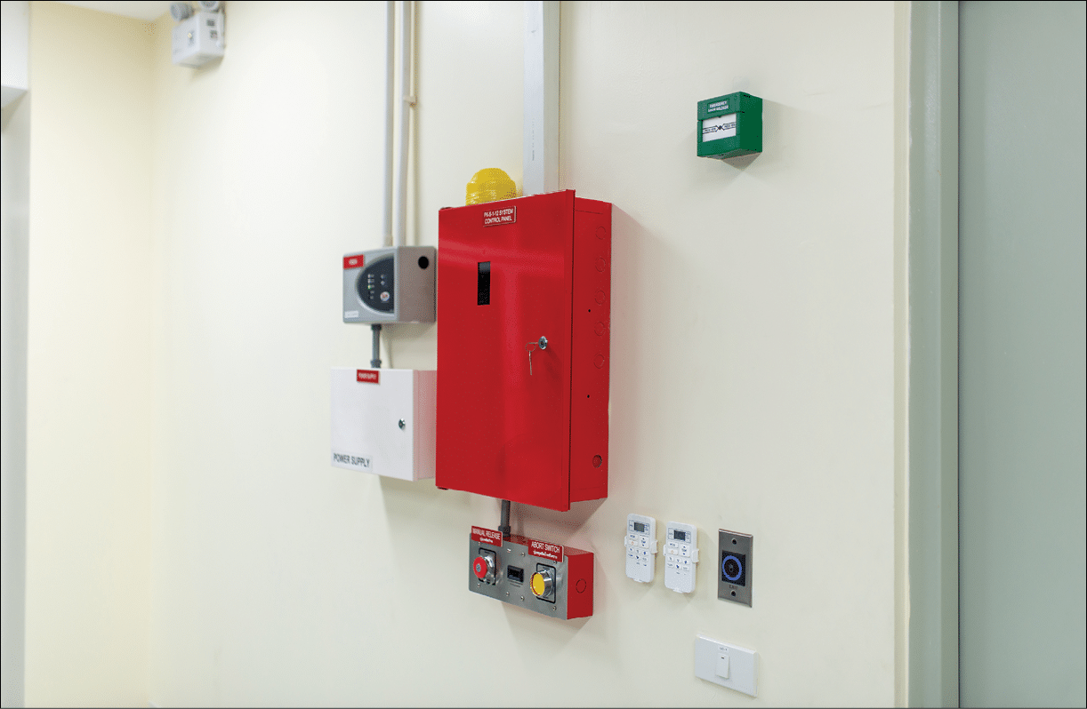 This image features fire safety equipment installed on the wall of a modern building, showcasing a red control panel and related devices for emergency response.